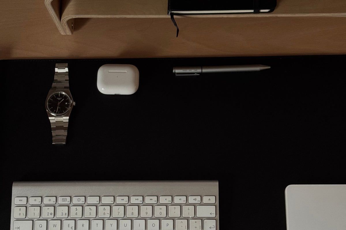 Escritorio despejado en tonos oscuros: teclado, cuaderno y pocos objetos elegidos, sin móvil a la vista.