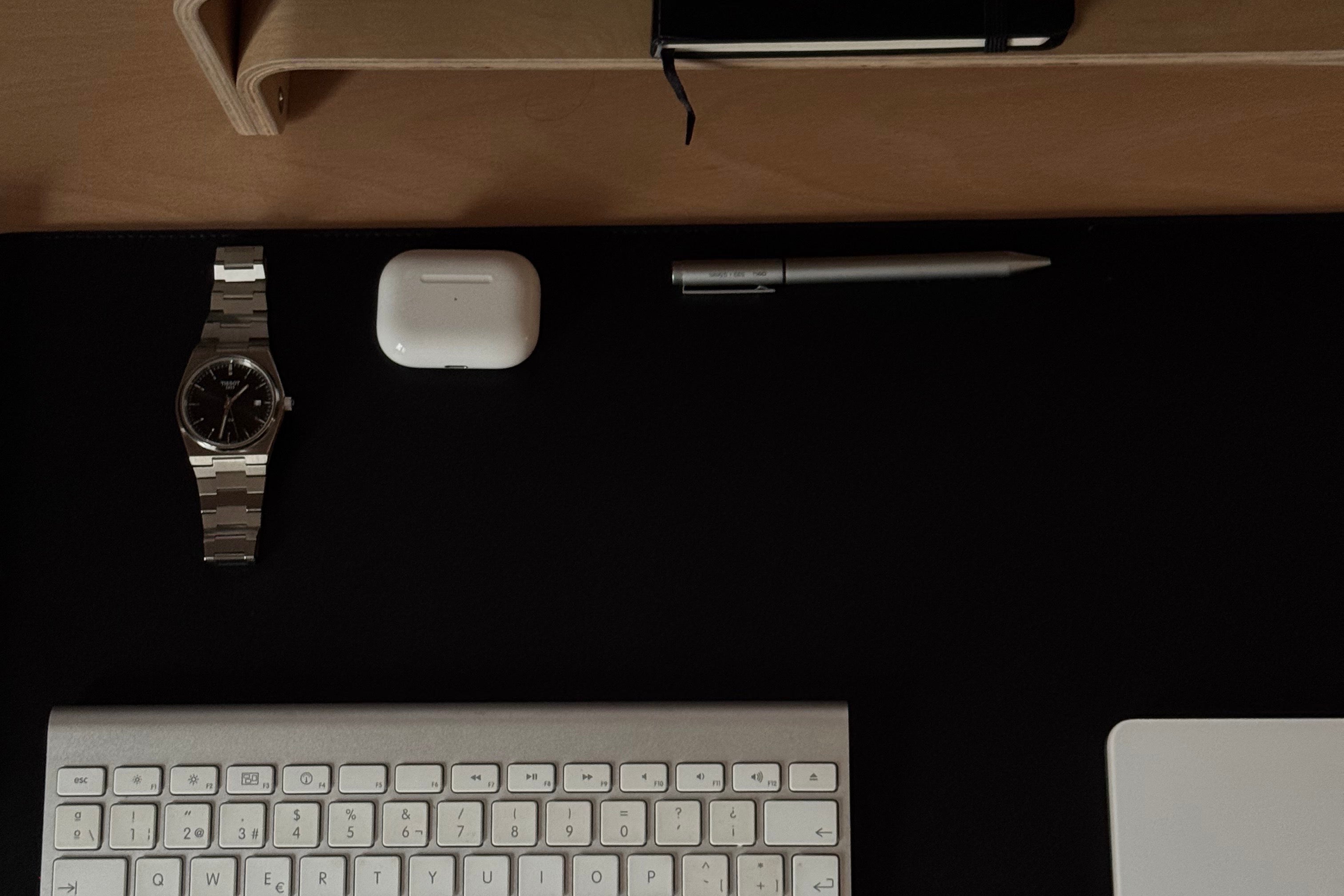 Escritorio despejado en tonos oscuros: teclado, cuaderno y pocos objetos elegidos, sin móvil a la vista.
